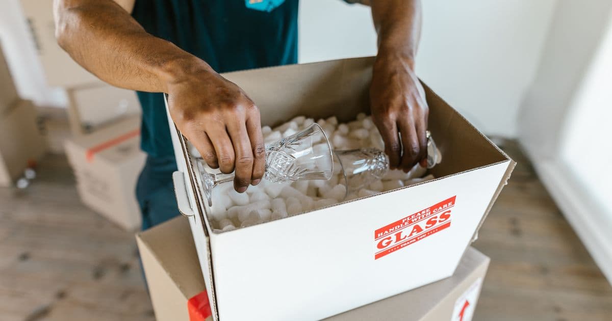 Professional mover packing glassware into a moving box