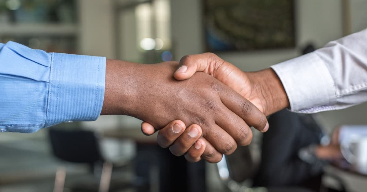 Two colleagues shaking hands in a bright office, representing handover between AI and human service teams